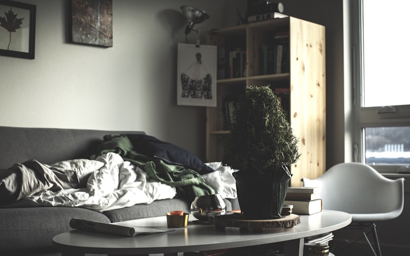 A cluttered Santa Barbara living room with clothing piled on the couch, a clear sign it's time to book a junk removal crew