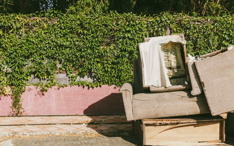 An old couch dumped against an ivy-covered wall, the kind of furniture our Santa Barbara crew hauls away